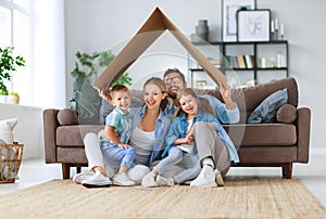 Concept of housing and relocation. happy family mother father and kids with roof at home