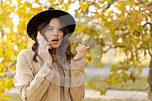 Concept of human frustration and sadness. Young sad beautiful woman calling on mobile phone in autumn park. Teenager