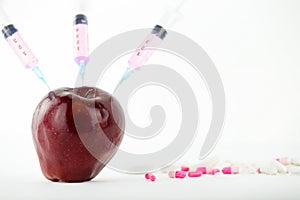 Concept: human GMO manipulation of nature and relative poisoned fruits. Close-up of an apple contaminated with a syringe threaded