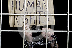 The concept of human rights freedom of speech hands shackled with an iron chain hold a microphone and a cardboard sign with the