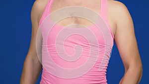 The concept of humor and parodies. A man in a pink vest with a deep neckline and a hairy chest, makes a dumbbell press