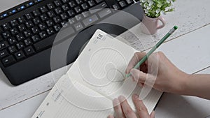 The concept of the idea, still life: a woman`s hand draws a light bulb in a notebook with a pencil