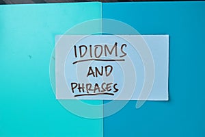 Concept of Idioms and Phrases write on sticky notes isolated on Wooden Table