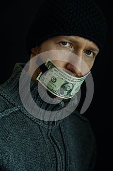 Concept image of corruption and bribery. Silent for money. Portrait of man with his mouth shut with one dollar banknote