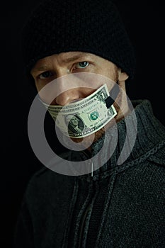 Concept image of corruption and bribery. Silent for money. Portrait of man with his mouth shut with one dollar banknote