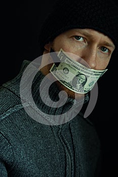 Concept image of corruption and bribery. Silent for money. Portrait of man with his mouth shut with one dollar banknote