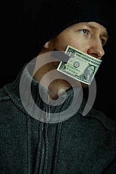 Concept image of corruption and bribery. Silent for money. Portrait of man with his mouth shut with one dollar banknote