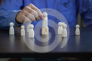 Concept image of a family leader holding a wooden puppet in front of a business team.