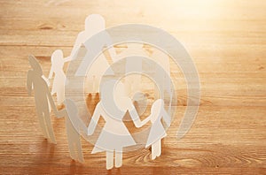 concept image of Family paper chain cutout holding hands, over wooden table.