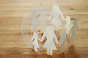 concept image of Family paper chain cutout holding hands, over wooden table.