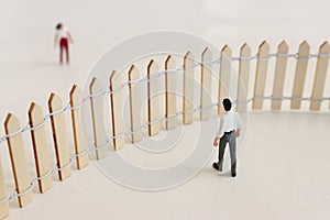 Concept image of a man seeing a woman across fence barrier that separates them. idea of relationship problems and disagreements