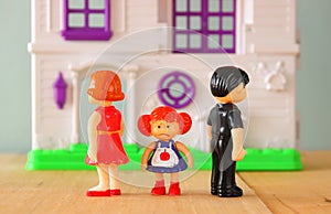 Concept image of parent busy or angry and child in the middle in front of. little plastic toy dolls (male , female, child)