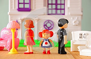 Concept image of parent busy or angry and child in the middle in front of. little plastic toy dolls (male , female, child) , selec