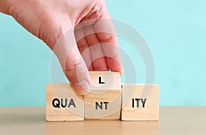 Concept image of quality management and performance with male hand picking wooden cube with text