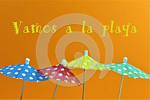 An concept Image of some umbrellas with the text, vamos a la playa = lets go to the beach Translation