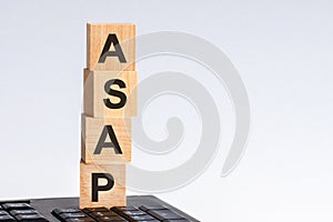 Concept image a wooden block and word Asap on white background. The cubes are located on the keyboard. Selective focus
