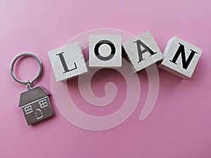 concept image a wooden block word - LOAN with keychain on pink background .