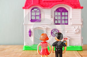 Concept image of young couple in front of new house. little plastic toy dolls (male and female) , selective focus.