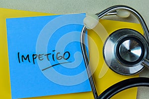 Concept of Impetigo write on sticky notes with stethoscope isolated on Wooden Table