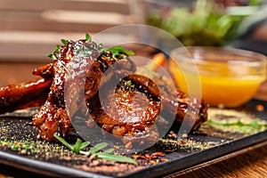 The concept of Indian cuisine. Baked chicken wings and legs in honey mustard sauce. Serving dishes in the restaurant