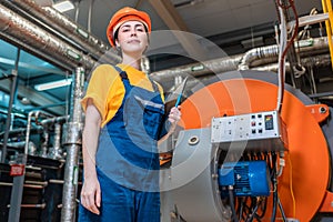 Concept of a industrial manufactory. A female smiling worker in uniform and helmet with a folder in her hand. In the background