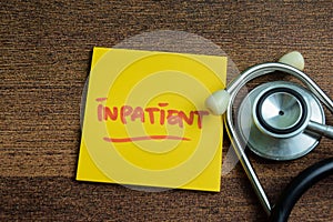 Concept of Inpatient write on sticky notes with stethoscope isolated on Wooden Table