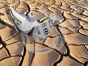 The concept of instability in business, the weakening of the dollar, a paper boat from a dollar bill in the desert