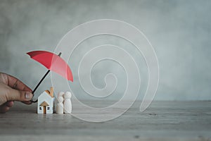 The concept of insurance for home and life. A small umbrella over the house and a family figure