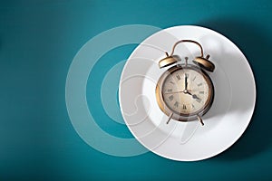 Concept of intermittent fasting, ketogenic diet, weight loss. alarmclock on a plate