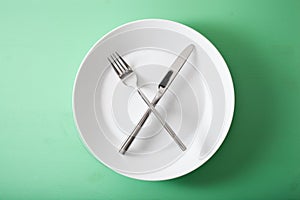 Concept of intermittent fasting and ketogenic diet, weight loss. fork and knife crossed on a plate photo