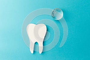 The concept of the International Day of the Dentist. Paper tooth and glass globe on a blue background. Top view