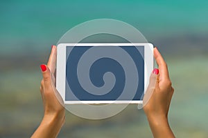 Concept of internet and communication. blank empty tablet computer in the hands of women on the beach