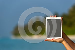 Concept of internet and communication. blank empty tablet computer in the hands of women on the beach