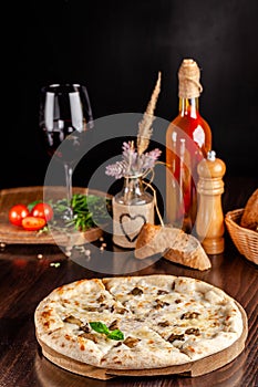 The concept of Italian cuisine. Thin cheese pizza with mushrooms, with large sides of Semola flour. A string of red wine