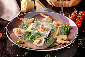 The concept of Italian cuisine. Tiger prawns on rice chips in a creamy sauce. Arugula salad and lemon