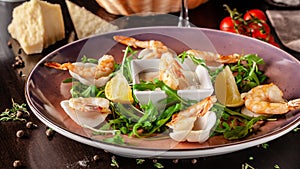 The concept of Italian cuisine. Tiger prawns on rice chips in a creamy sauce. Arugula salad and lemon