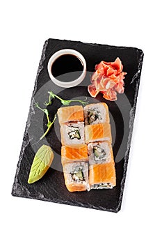 The concept of Japanese cuisine. Rolls with salmon, feta cheese, cucumber. Near soy sauce, ginger and wasabi. Modern serving