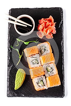 The concept of Japanese cuisine. Rolls with salmon, feta cheese, cucumber. Near soy sauce, ginger and wasabi. Modern serving