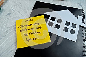 Concept of Jetzt Warmepumpe Einbauen und heizkosten sparen write on sticky notes isolated on Wooden Table photo