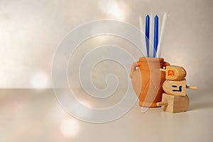 Concept of of jewish religion holiday hanukkah with wooden spinning top toys dreidels, small clay jar with blue and white