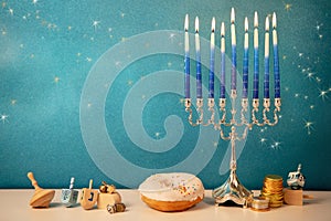 Concept of of jewish religious holiday hanukkah with glittering raditional chandelier menorah, spinning top toys dreidel, a