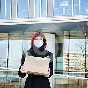 Concept of job loss due to the COVID-19 virus pandemic. Woman in mask with box of his things