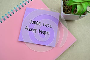 Concept of Judge Less Accept More write on sticky notes isolated on Wooden Table