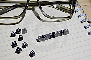 Concept of Kalender in Germany on wooden cubes with glass eye, books in Vintage background