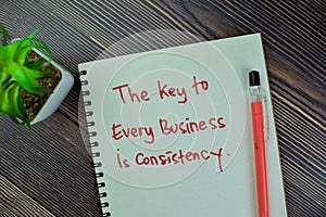 Concept of The Key to Every Business is Consistency write on a book isolated on Wooden Table