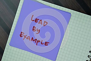 Concept of Lead by Example write on sticky notes isolated on Wooden Table