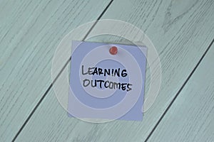 Concept of Learning Outcomes write on sticky notes isolated on Wooden Table