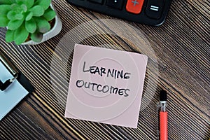 Concept of Learning Outcomes write on sticky notes isolated on Wooden Table