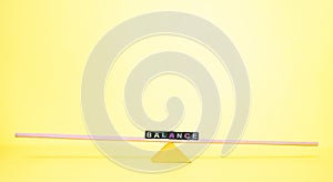 Concept of a lever and fulcrum, of balance, equilibrium and equality on yellow background with copyspace