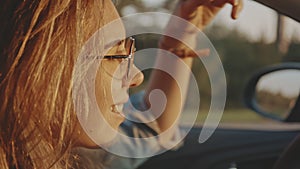 Concept of lifestyle and beauty. Close-up of adorable young blonde face wearing stylish sunglasses driving her car at